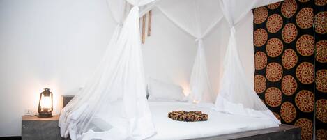 A bed with a white canopy, a patterned rug, and a wall with a circular design.