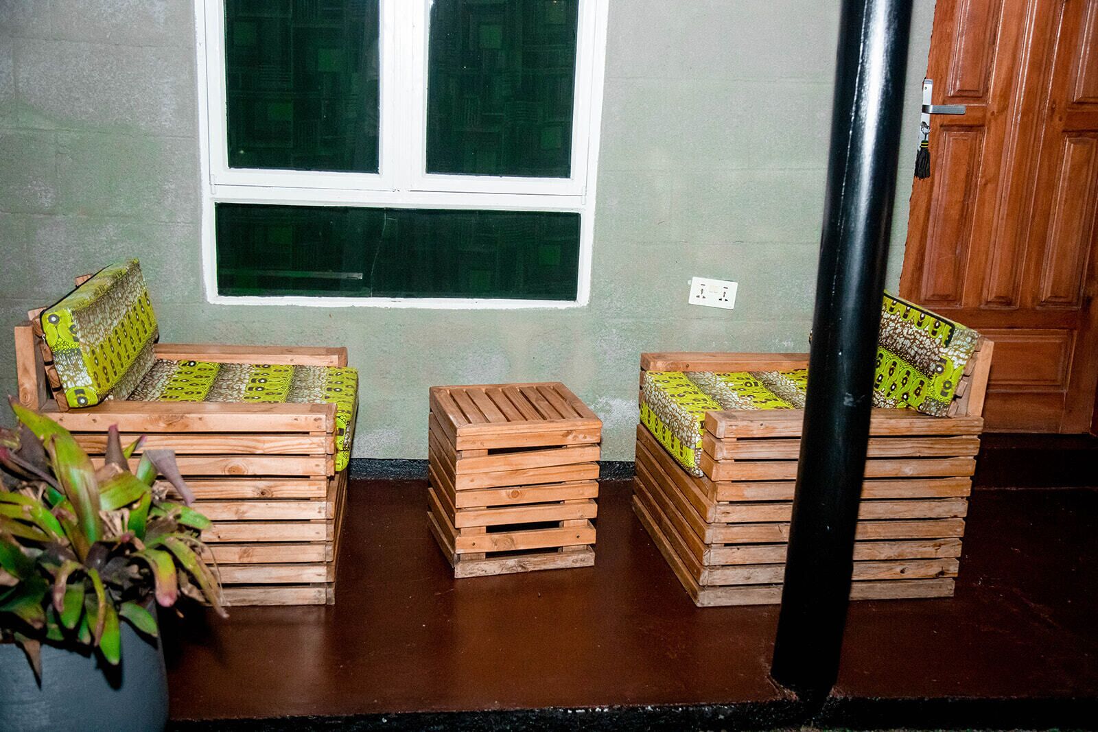 Una habitación con dos bancos de madera, una mesa pequeña, una ventana y una puerta.