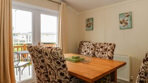 Un coin repas avec des chaises à motifs, une table en bois et une vue sur un balcon.