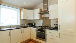 Une cuisine moderne avec des armoires blanches, une hotte en acier inoxydable, une cuisinière à gaz et un four encastré.