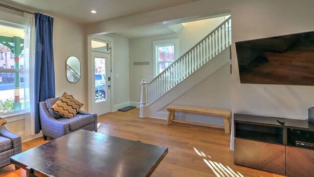 Un salon moderne avec un plancher en bois, une table à manger, un canapé et un escalier menant à une autre pièce.