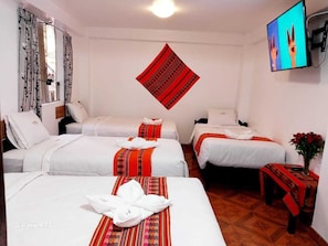 A hotel room with three beds, a flat-screen TV, and a red patterned wall hanging. - HOTEL VALLE DORADO  (Machu Picchu)