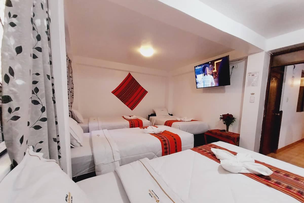 A hotel room with two beds, a TV on the wall, and a red decorative wall hanging.
