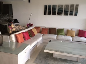 A modern living room with a sectional sofa, a glass coffee table, and a decorative sculpture.