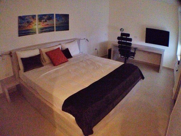A bedroom with a bed, a desk, and a TV.