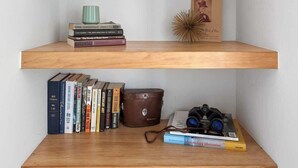 Un ensemble d’étagères en bois avec des livres, une tasse verte, une petite plante en pot et un objet décoratif.