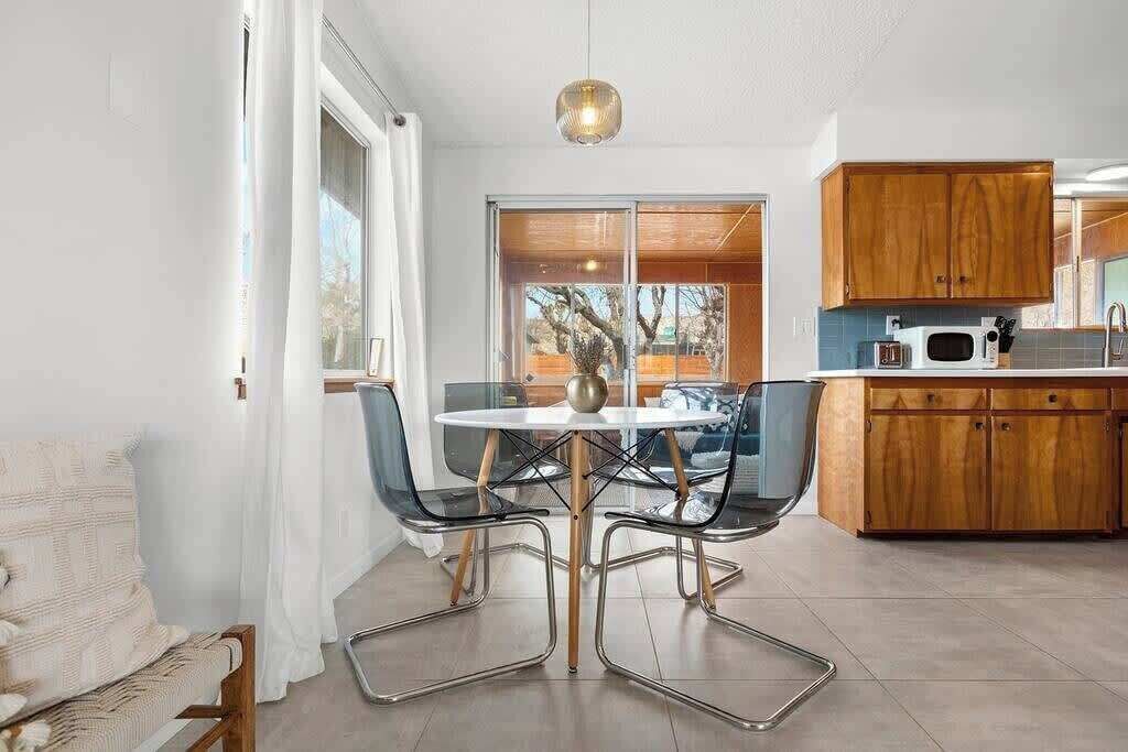 A modern kitchen with wooden cabinets, a round dining table, and a hanging pendant light.