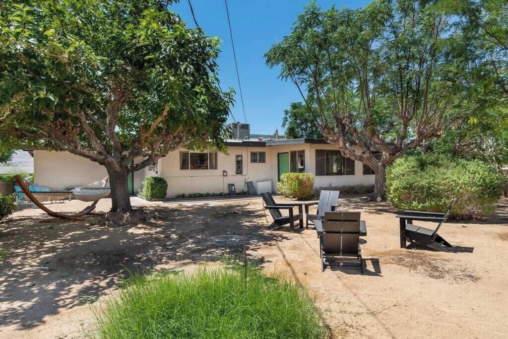 A house with a patio area, outdoor furniture, and a tree.