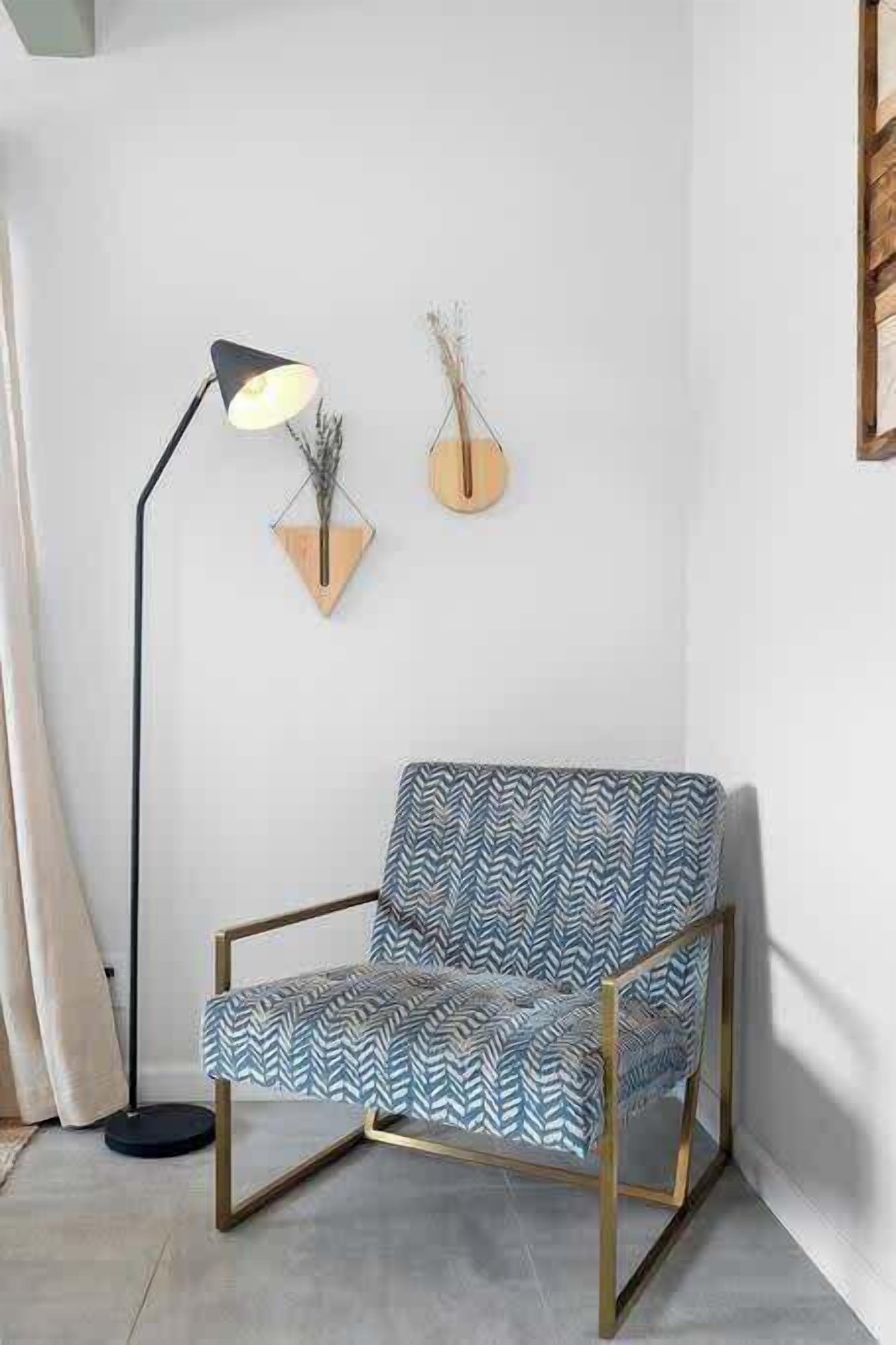A chair with a geometric pattern, a floor lamp, and two wall-mounted decorations.