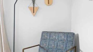A chair with a geometric pattern, a floor lamp, and two wall-mounted decorations.