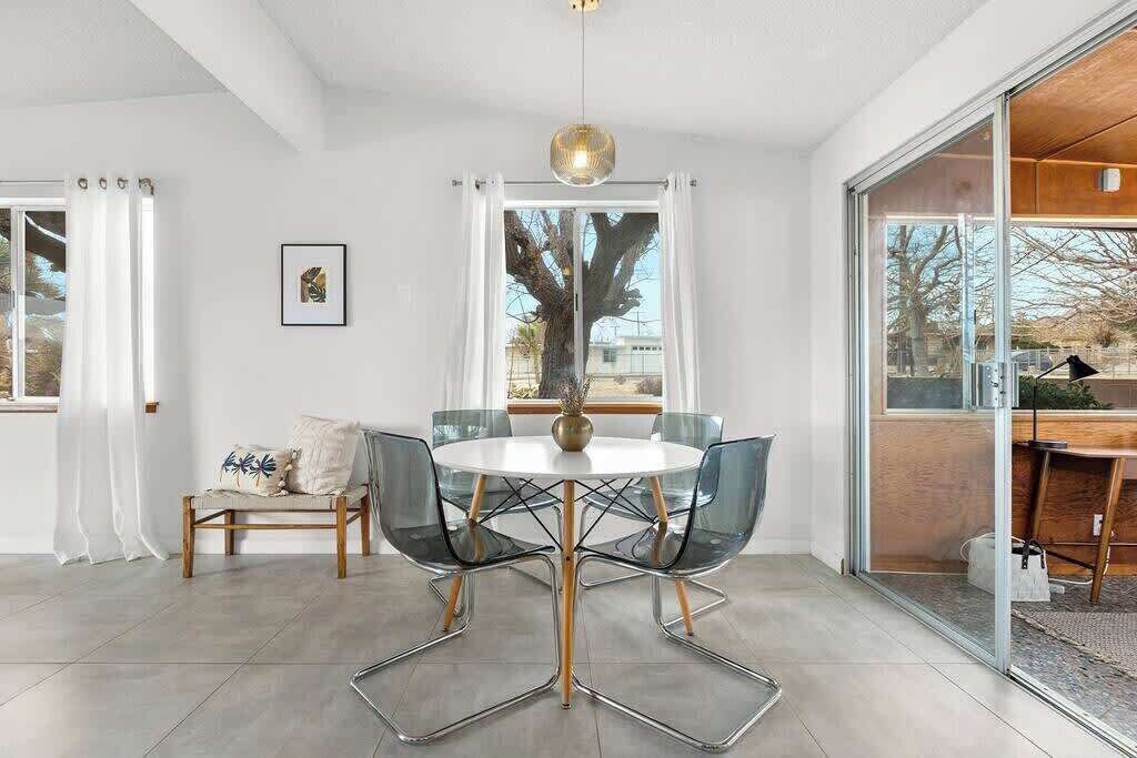 A modern dining area with a round table, clear chairs, and a pendant light.