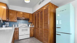 A kitchen with wooden cabinets, a white stove, a blue refrigerator, and a tiled backsplash. - Moonrise Ranch|Yoga Sun Room|Cowboy Pool (Joshua Tree)