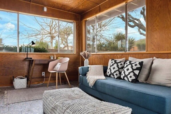 A cozy room with a blue sofa, a desk, and a chair.