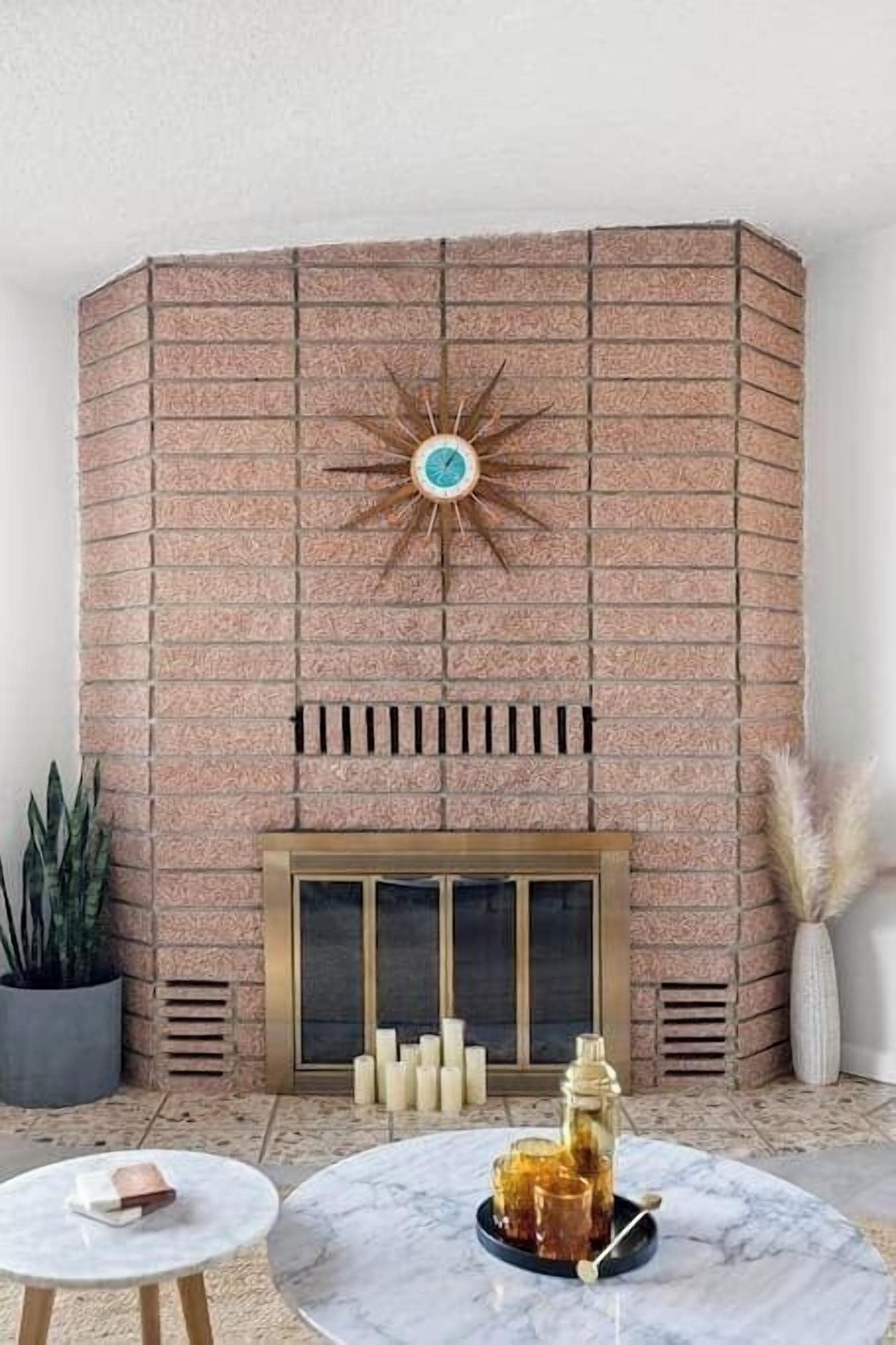 A brick fireplace with a star-shaped decoration, a glass door, and a small table with candles and a vase of dried plants.
