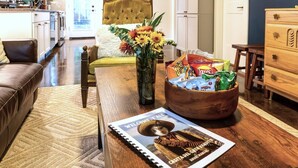 A wooden dining table with a magazine, a vase with flowers, and a bowl of snacks. - El Gato Bandito (Denton)