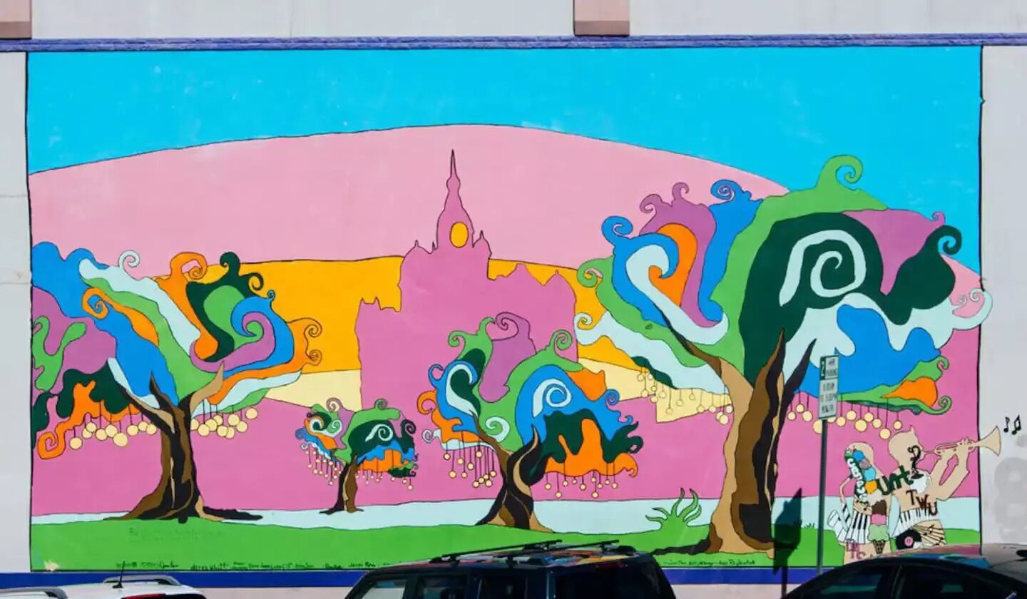 Un mural colorido con árboles y una figura tocando una trompeta.