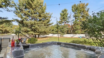 A hot tub with a clear view of the surrounding yard, including trees and a fenced area.
