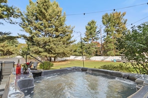 A hot tub with a clear view of the surrounding yard, including trees and a fenced area.