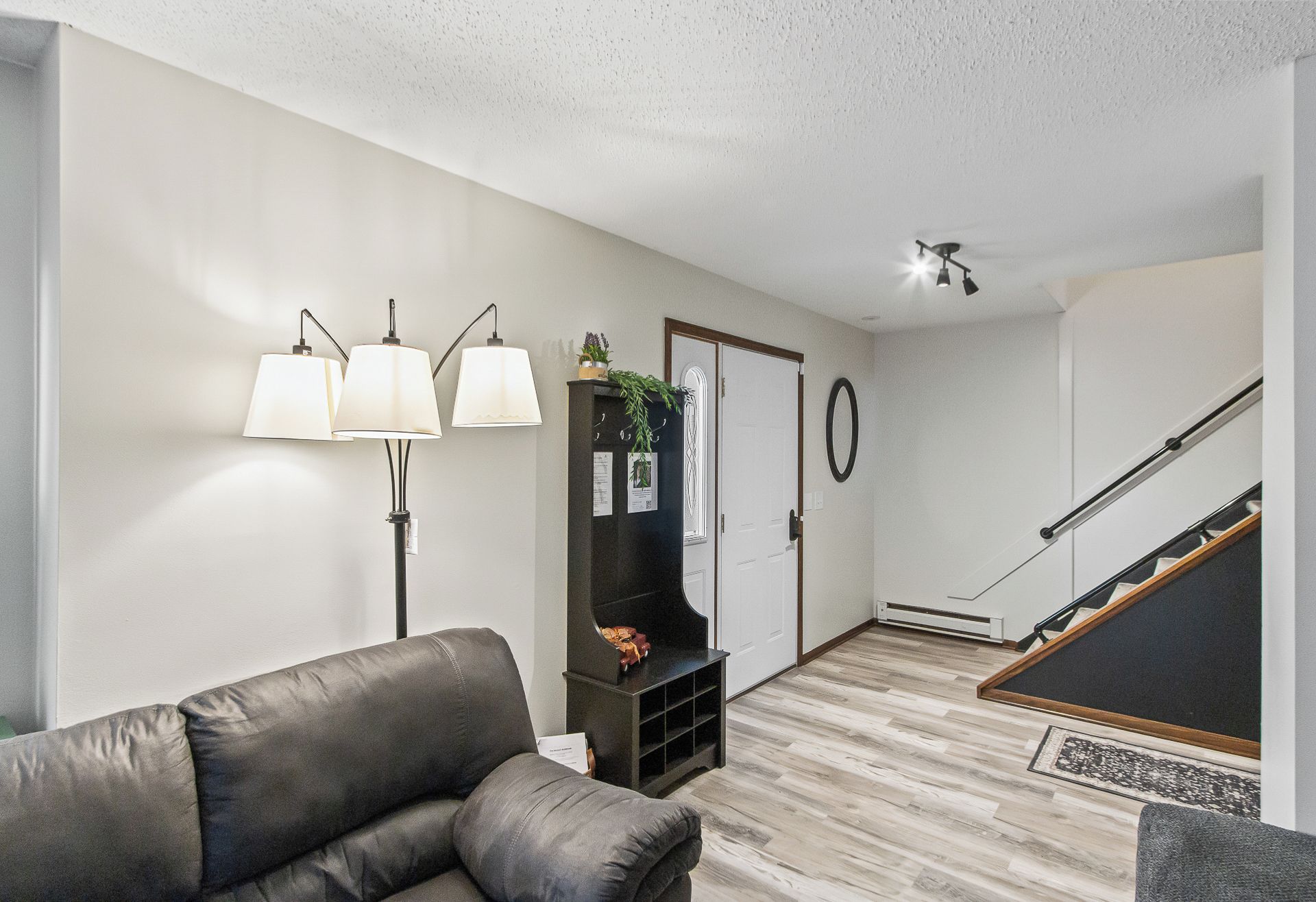 A living room with a sofa, a lamp, a bookshelf, and a staircase.