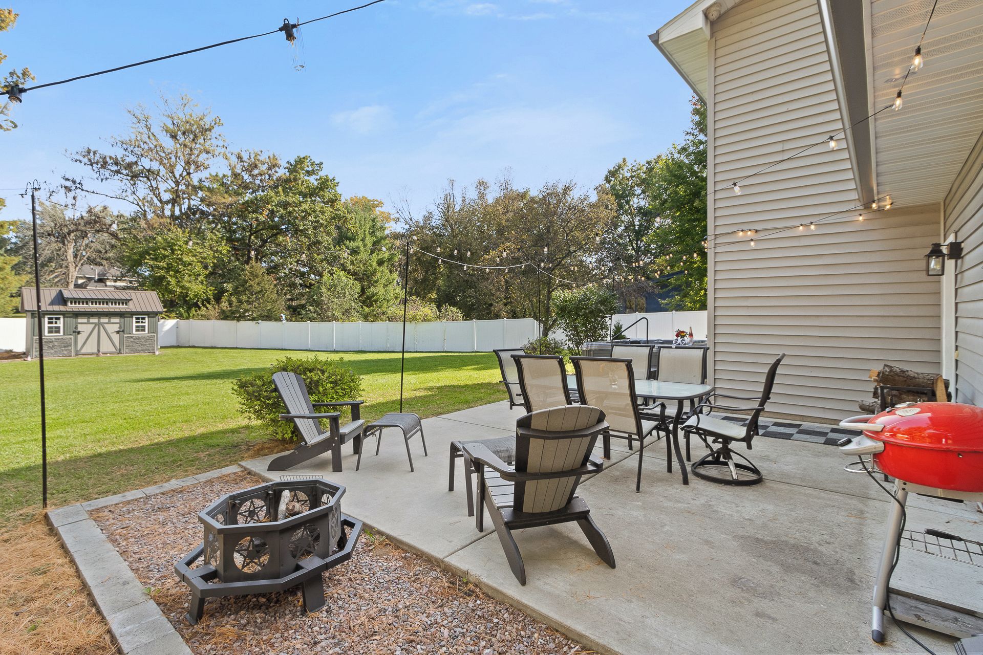 Spacious fenced backyard patio with fire pit, grill, and outdoor dining