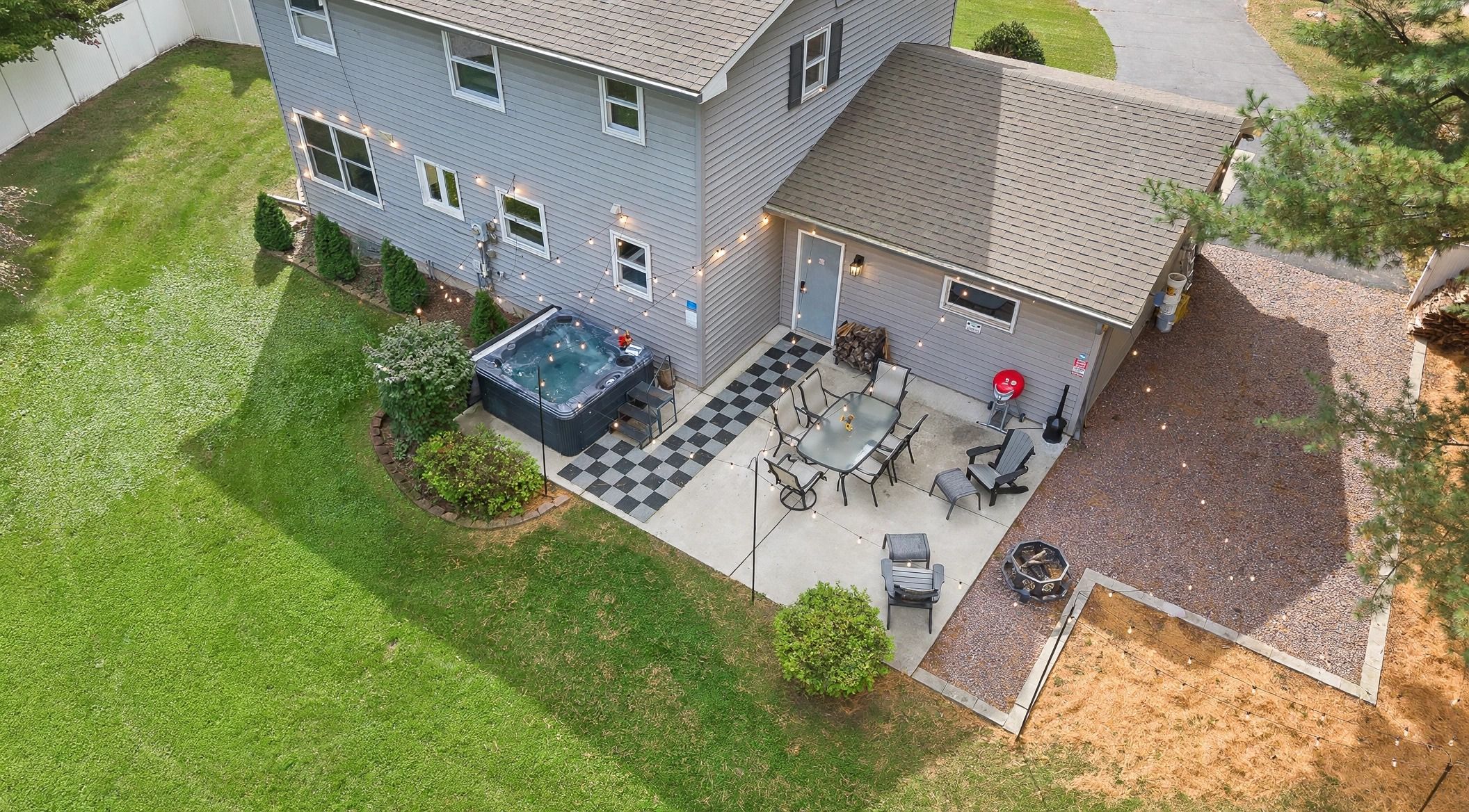 A residential property with a patio area featuring a hot tub, outdoor seating, and a fire pit.