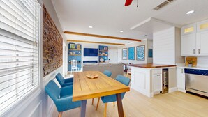Una cocina moderna con armarios blancos, una isla de madera y sillas azules alrededor de una mesa de madera.
