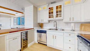 Una cocina moderna con armarios blancos, electrodomésticos de acero inoxidable y encimera de madera.