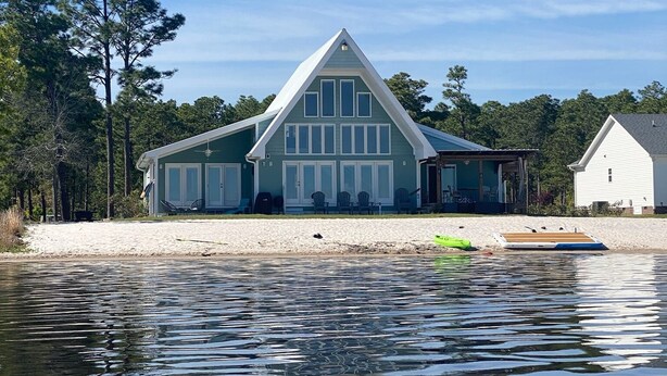 A large house with a gabled roof, a covered porch, and a sandy beach in front. - Lake front living with private sandy beach! (Elizabethtown)