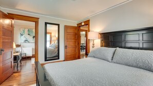 A bedroom with a large bed, wooden door, and a view of a dining area. - Spacious Home in Ramsay: 9 Smart TVs + Pool Table! (Ramsay)