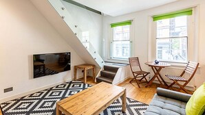 Un salon moderne avec un escalier, un téléviseur à écran plat, une table basse en bois et un canapé.