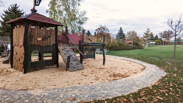 Une aire de jeux avec une cabane en bois et des structures d’escalade.