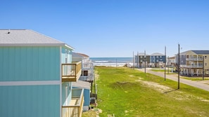 Un quartier résidentiel en bord de mer, avec des maisons, une pelouse verdoyante et une vue dégagée sur l’océan.