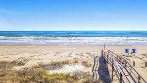 A beach with a wooden walkway leading to two blue beach chairs. - Family Beach Retreat Steps From Surfside Waves (Surfside Beach)