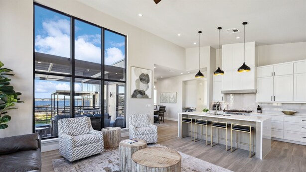 Una cocina moderna con armarios blancos, una isla central e iluminación colgante.