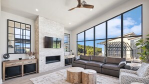Una sala de estar moderna con chimenea, ventanas amplias y vistas al exterior.