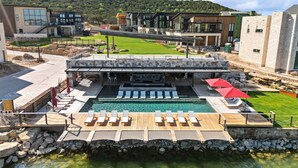 Un hotel moderno con zona de piscina, mobiliario exterior y vistas del paisaje circundante.