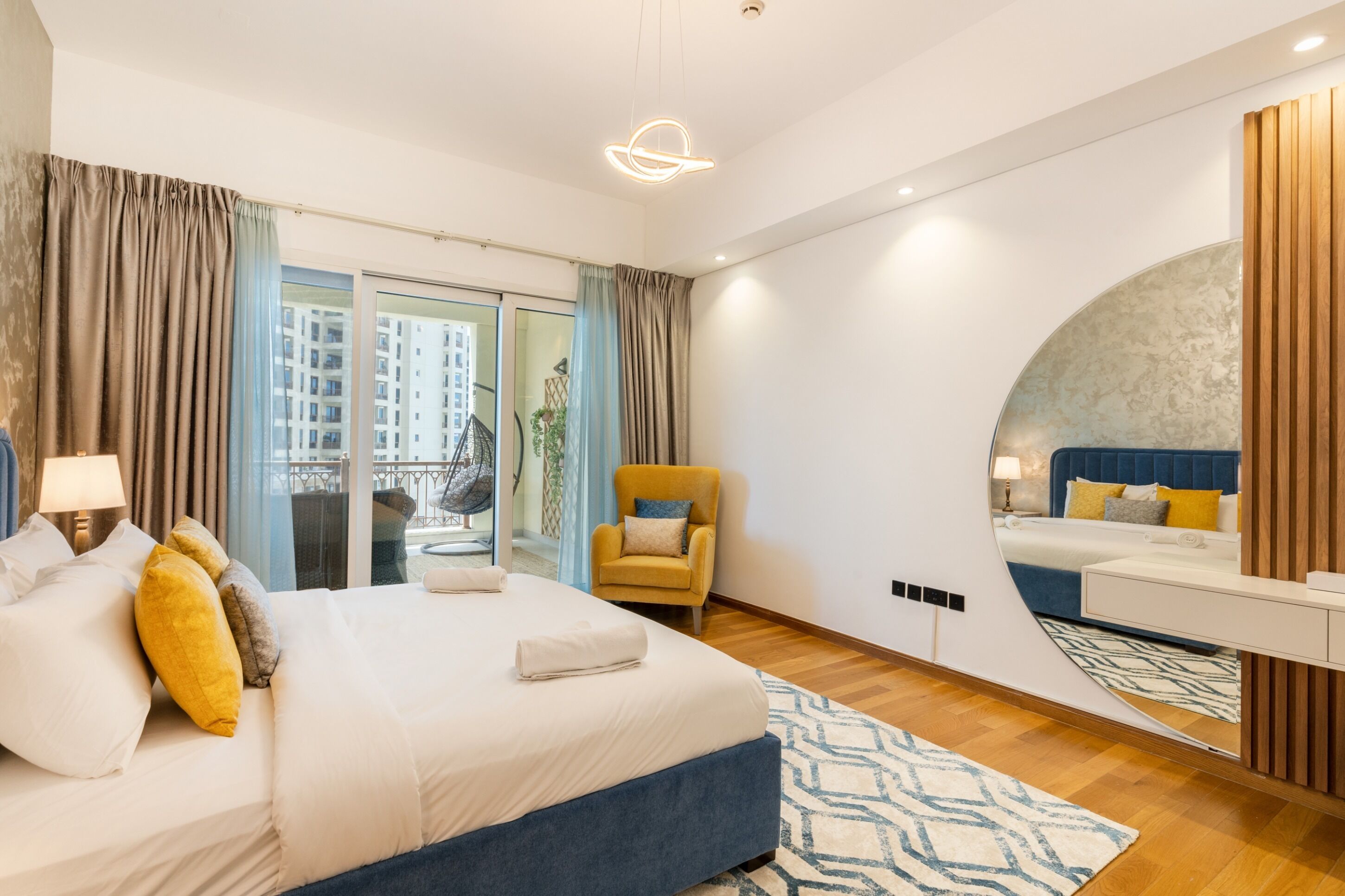 Une chambre d’hôtel moderne, dotée d’un grand lit, d’une chaise, d’un bureau et offrant une vue sur la ville par la fenêtre.