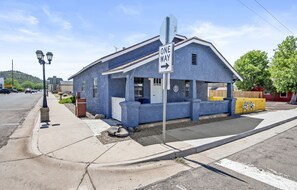 A blue building with a 'ONE WAY' sign, a sidewalk, and a street. - Route 66 Downtown Blue Bungalow w/Fenced Yard, AC, W/D, 4 Smart TVs, Fast Wi-Fi (Williams)