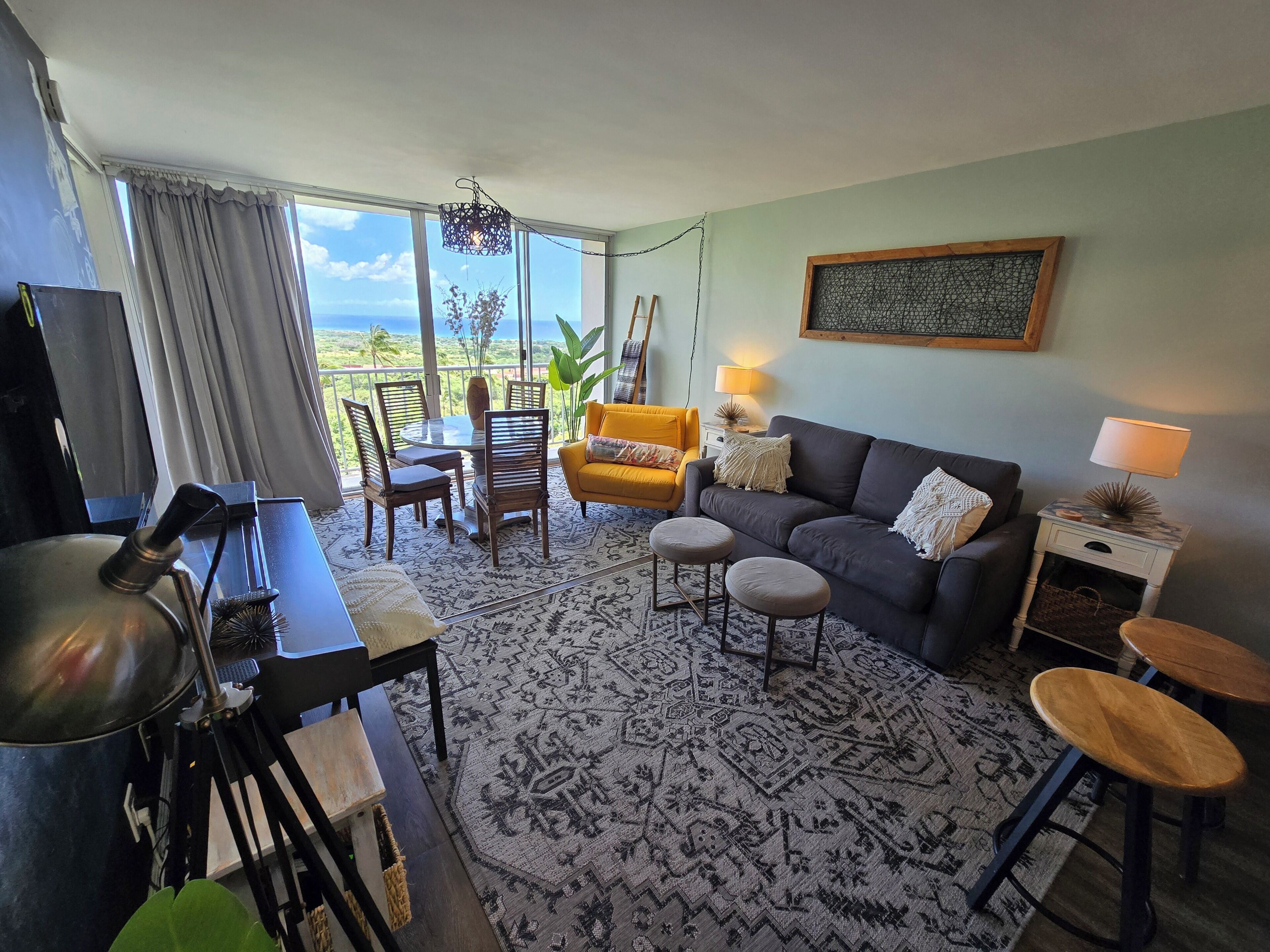 Un salon comprenant un canapé, des fauteuils, une table à manger, une lampe et une vue sur l’extérieur.