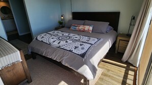 Een slaapkamer met een bed, nachtkastje, hanglamp en uitzicht.