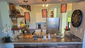Een moderne keuken met een centraal eiland, roestvrijstalen apparatuur, hangende吊り下げ式ライト, en houten barkrukken.