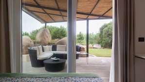 A room with a bed, a large window, and a view of an outdoor seating area with a sofa and a table. - Cozy House close to the sea (Foxi Lioni)