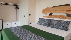 A bedroom with a bed, a wooden headboard, a nightstand, a dresser, and an air conditioning unit. - Cozy House close to the sea (Foxi Lioni)