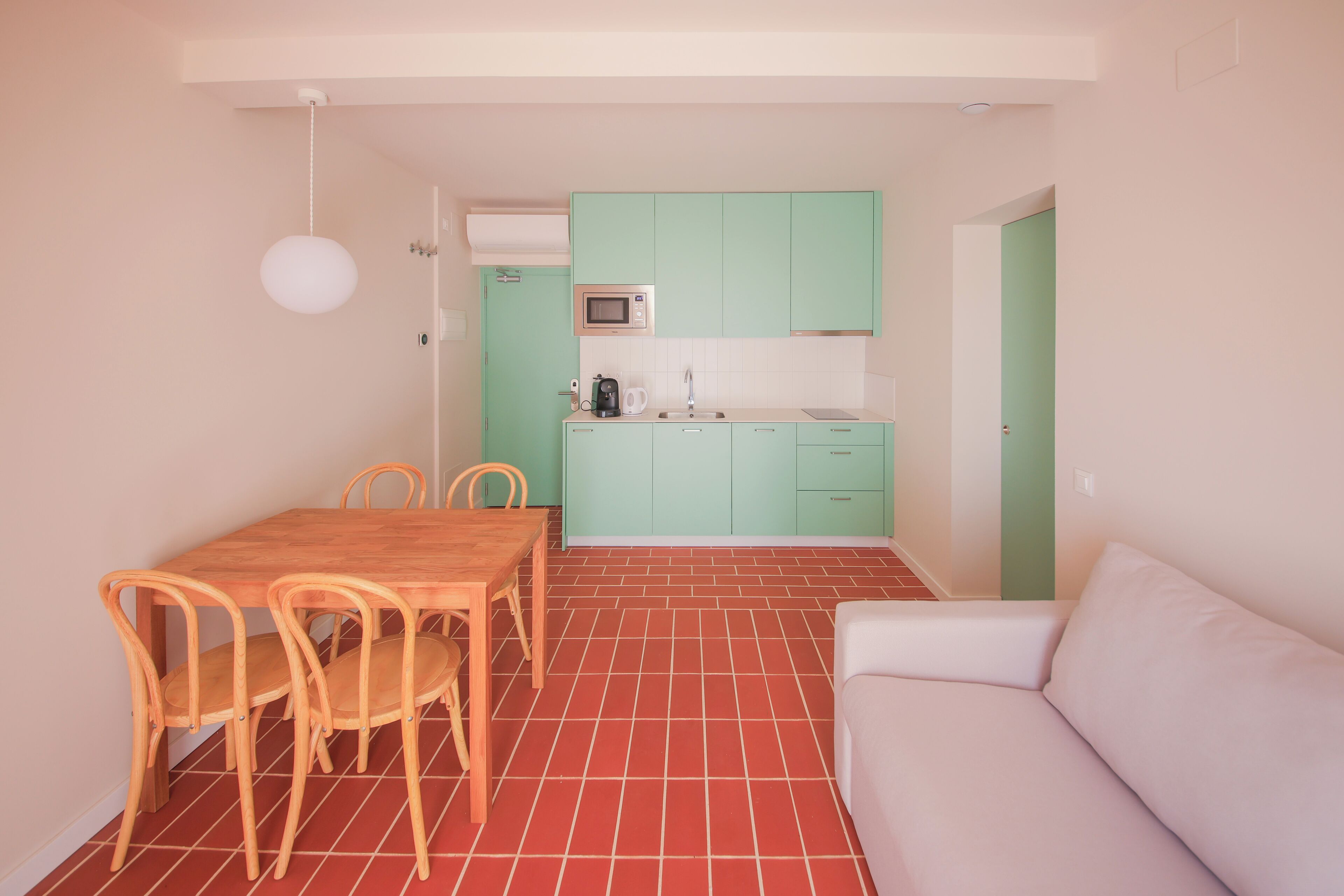 A compact living space with a dining area, kitchenette, and a sofa.