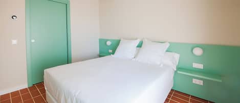 Une chambre avec un lit, une tête de lit verte, un matelas blanc et une porte verte.