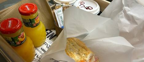 Una caja con un sándwich, dos botellas de Granini y sobrecitas de azúcar.