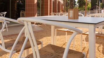 Un espace extérieur aménagé avec des chaises et des tables en métal blanc, entouré de galets.