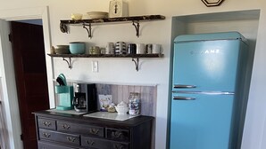 A kitchen with a dark wooden dresser, a teal refrigerator, and a coffee maker on the counter. - Bubba Butler's Cottage (Locust Hill)