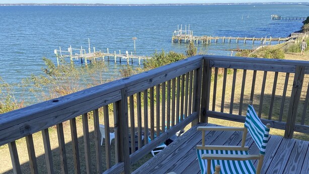 A wooden deck with two striped beach chairs facing a calm body of water. - Bubba Butler's Cottage (Locust Hill)