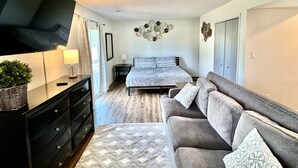 A bedroom with a bed, a TV, a sofa, and a dresser. - Mid city huntsvegas studio #2 (Huntsville)